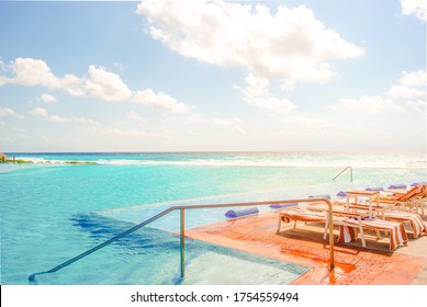 Big Infinity Pool With Salt Water In The Caribbean Sea In Bright Sunny Afternoon. Summer Tropical Ocean Location Getaway. Turquoise Blue Water And Orange Red Deck Chairs. Hotel No People