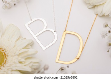 Big Initials Necklace On White Background Flowers Decorated . Silver Necklace Photo For Ecommerce.