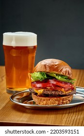 A Big Juicy Burger With Vegetables And A Glass Of Beer. Close-up, Selective Focus