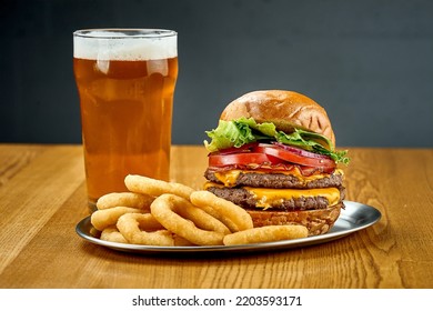 A Big Juicy Burger With Vegetables And A Glass Of Beer. Close-up, Selective Focus