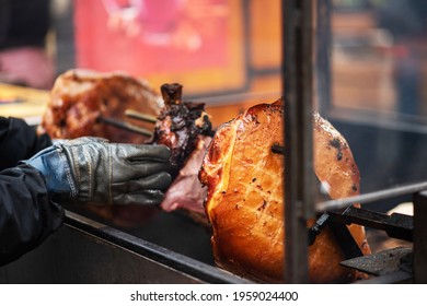 Big Juicy Pork Leg On The Grill. Prague Christmas Fair. Traditional Czech Food. National Cuisine. The Street Food. Roasted Smoked Pork Leg Ham Grilling In Street Food Market At Prague, Czech Republic