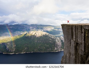Big jump on The Pulpit Rock / Prekestolen in Norway with a rainbow - Shutterstock ID 1212161704
