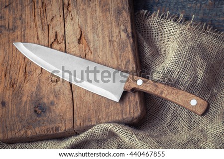 Big kitchen knife lying on an old cutting board