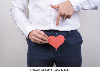 Big large long pleasure intimate intimacy size concept. Cropped close up photo portrait of handsome happy smiling satisfied gentleman showing holding heart near trousers isolated grey background