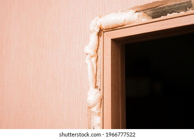 Big layer of polyurethane foam around door hole around just installed wooden door with glass inserts in the room. Installation. Polyurethane foam. Expand. Particular-foam. Expanding. Material