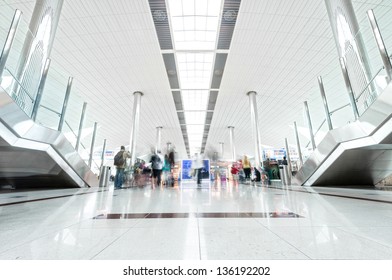 Big light hall in Dubai airport with passengers in hurry. United Arab Emirates. Modern style interior with shining metal constructions and lot of light. Travelling and tourism.