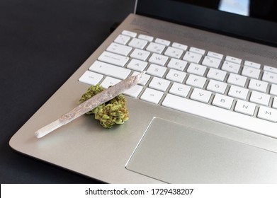 Big marijuana joint and cannabis buds on laptop on black background, Concept of cannabis and technology.