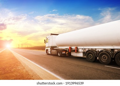 Big Metal Fuel Tanker Truck Shipping Fuel On The Countryside Road Against A Night Sky With A Sunset