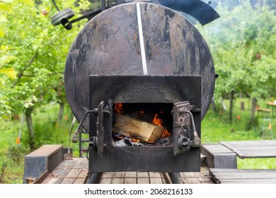 big metal smoker outdoor with open door to a log burning