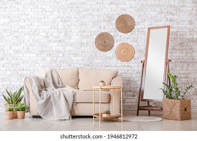 Big Mirror With Sofa Near Brick Wall In Room