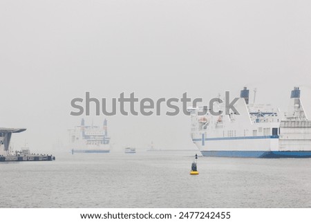 Big modern ferry ship navigate from Rostock harbor Warnemunde bay foggy spring autumn morning misty weather scenic view background. Maritime traffic liner passenger cargo vessel at Baltic sea Germany