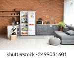 Big modern fridge with fresh products on brown brick background in kitchen