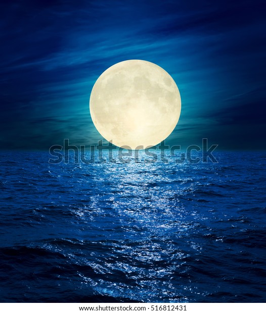 big moon in clouds over\
night sea