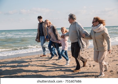 Big Multigenerational Family Holding Hands And Running Together On Beach At Seaside