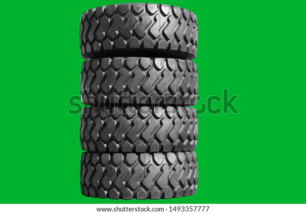 Big new tires for trucks. Car\
tires with a large tread are in a row. Isolated green\
background.