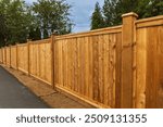 Big new wooden fence around the house and trees. Wooden fence with green trees . Fencing and gates. High quality fence. Street photo