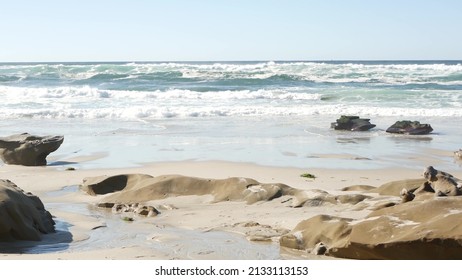 Big ocean waves crashing on beach, La Jolla shore, California coast, USA. Eroded stones or rocks on sandy pacific coastline. Sea water foam splashing, summertime aesthetic. Seascape or landscape