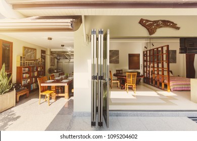 Big Open Dining Room With Bookshelf And Bedroom With Folding Doors In Luxury Villa Hotel Resort. Summer, Tropical Wether, Sun Light, Outdoor Space 