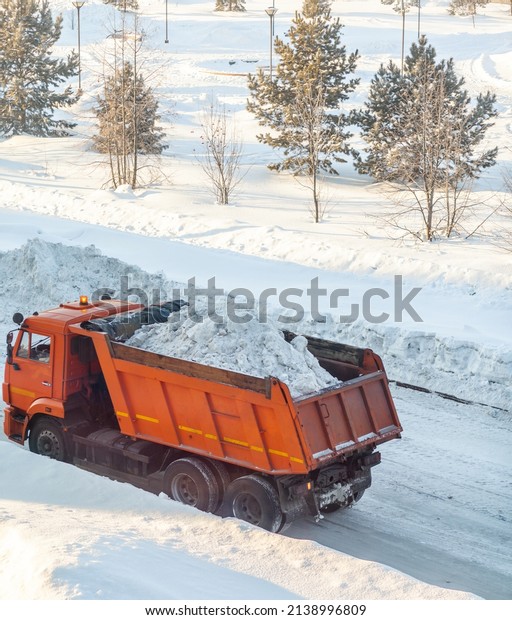 A big orange truck\
takes snow off the road. Cleaning and cleaning of roads in the city\
from snow in winter