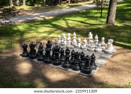 Big outdoor chess on in the park on a sunny day. Sport game. Landscape design. Public place with leisure. Large chessboard and plastic figures.