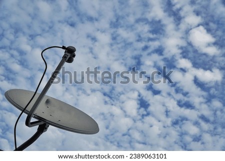 Big parabolic antenna against dramatic sky, blue sky