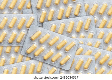 Big pharma metal tablet blister. Yellow pills medicine. Silver shiny blister with drugs. Transparent capsules in blister pack closeup. Yellow medicament texture. Aluminum pills blister. - Powered by Shutterstock