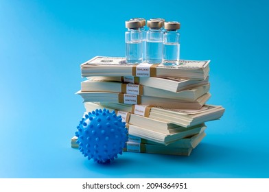 Big Pharma Profiteering, Healthcare Corruption And Pharmaceutical Industry Greed Concept With Vaccine Vials On Top Of Huge Pile Of Money And Coronavirus Model Isolated On Blue Background