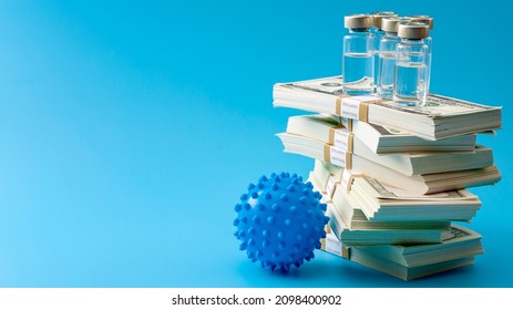 Big Pharma Profiteering, Healthcare Corruption And Pharmaceutical Industry Greed Concept With Vaccine Vials On Top Of Huge Pile Of Money And Coronavirus Isolated On Blue Background With Copy Space