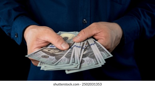 Big pile of money dollars in the hand. Close up of businessman counts money in hands. American Dollars Cash Money. 100 dollars banknotes in the background.