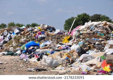 Big pile of unsorted garbage under the sun in municipal landfill in summer day, selective focus