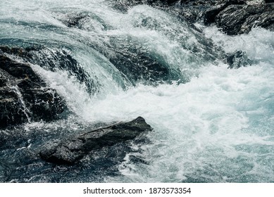 Big rapids of powerful mountain river. Beautiful background with azure water in fast river. Frozen motion of tall mountain river rapids. Power majestic nature of highlands. Backdrop of aqua turbulence