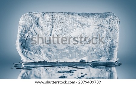 A big rectangular textured transparent piece of ice on a blue background.