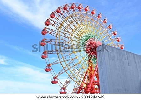 Big red Ferris wheel against white and blue sky names 