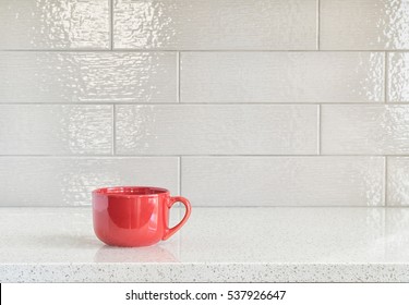 A Big Red Mug On Granite Counter Top Against Ceramic Backsplash