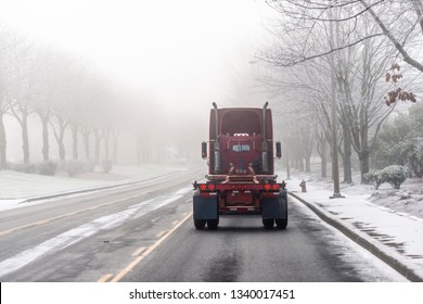 Big rig American classic long haul semi truck tractor without semi trailer driving on straight snow slippery winter road with dense fog going to warehouse for pick up loaded semi trailer