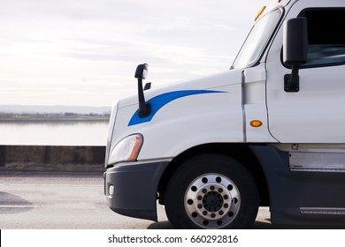 Big Rig American King Of Roads White Semi Truck Driving By Interstate Highway With Columbia River View In Sunshine. Side View With Perfection Details