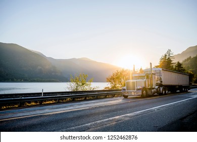 Big Rig American White Long Haul Powerful Semi Truck Transporting Commercial Cargo In Bulk Semi Trailer On Straight Evening Road With Scenic Sunset In Columbia River Gorge