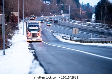 Big Rig Classic American Fleet Bonnet Semi Truck With Head Light Turned On And Refrigerated Semi Trailer Standing On The Shoulder Of The Highway Exit In Snow Winter Weather