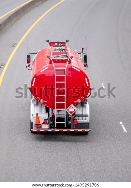 Big rig day\
cab industrial grade semi truck transporting tank semi trailer\
designed for the safe transport of chemicals and fuel driving on\
the divided wide turning\
highway