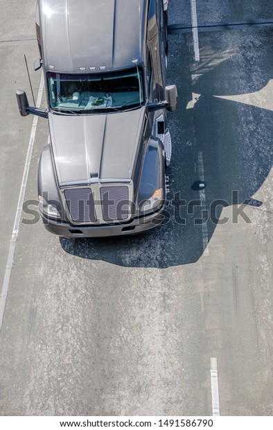 Big rig gray long haul bonnet professional heavy-duty\
semi truck transporting commercial cargo in dry van semi trailer\
for delivery driving on the left line of wide multiline highway in\
sunny day