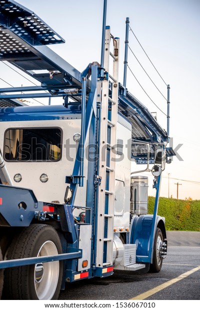 Big rig industrial grade car hauler American\
bonnet semi truck with empty semi trailer stands on the truck stop\
parking lot waiting for continue go to the vehicle loading point\
for next delivery