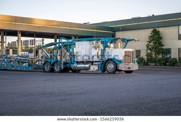 Big rig industrial grade car hauler classic\
American bonnet semi truck with empty semi trailer stands on the\
fuel station for refueling and continue to the vehicle loading\
point for next delivery