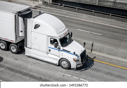 Big rig long haul white semi truck transporting frozen food in refrigerated semi trailer with refrigerator unit on the front wall running on the wide interstate highway road with intersection - Shutterstock ID 1491586772
