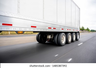 Big Rig Powerful Semi Truck Transports A Heavy-duty Four-axle Semi Trailer For Transporting Heavy Loads And Axle Weight Distribution Running On The Straight Wide Multiline Highway