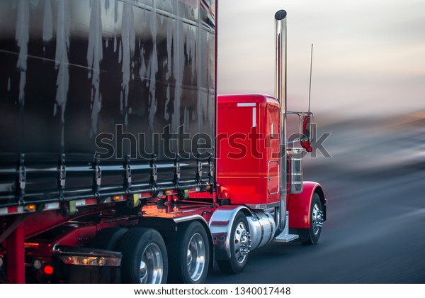 大型の赤いアメリカの伝統的なボンネットロングホールラーセミトラックで ゴム化した布で覆われた黒いセミトレーラーが雨の降る道を移動し 雨の埃がぼやけた霞が積み込み倉庫に向かう の写真素材 今すぐ編集