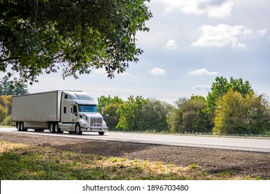 Big rig white long haul industrial semi truck tractor with sleeper cab compartment for truck driver rest transporting cargo in dry van semi trailer driving on the highway road with autumn trees - Shutterstock ID 1896703480