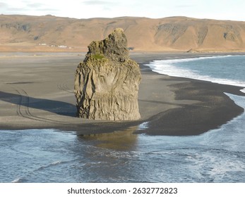 Big rock stack on black sand beach.