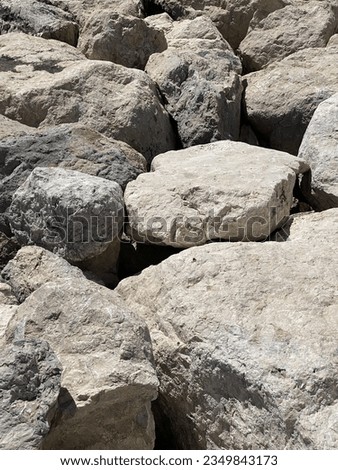Big rocks by the Mediterranean Sea in the shore in Split, Croatia. Rocks have different tones of beige and gray. Sun is shining brightly on a hot summer day in Europe. European vacation atmosphere
