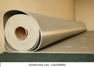 a big roll of carpet underlayer on the green floor 