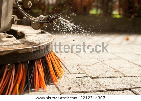 Big round brush of a street sweeper ,close up. Urban street cleaning, with motion blur 